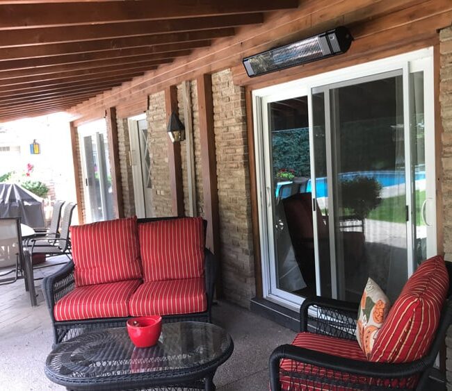 Electric patio heaters in a residential outdoor setting with red chairs.
